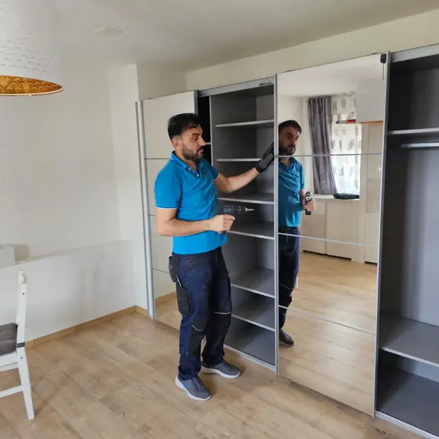 Deux déménageurs montent une armoire dans le nouveau logement