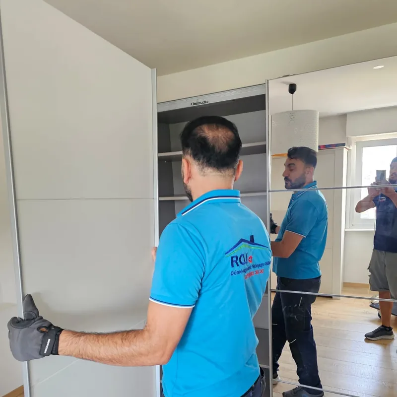 Deux déménageurs portent un panneau d'armoire dans l'appartement